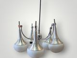 three white glass lamps hanging from a metal pole on a wall