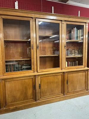 une grande bibliothèque en bois avec des portes vitrées dans une pièce