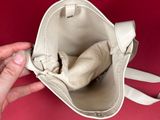 a person holding a white purse with a cat inside of it