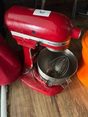 un mixeur rouge posé sur une table en bois, à côté d'un chapeau orange