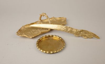 a gold plate with a feather on it next to a bottle opener