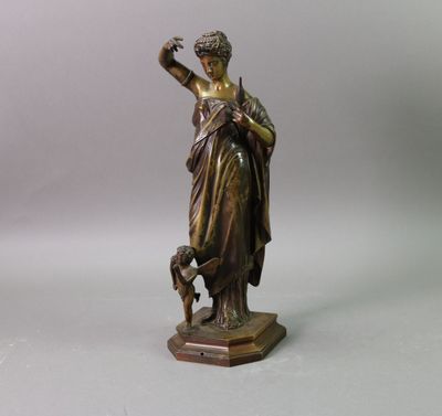 une statue antique en bronze représentant une femme tenant un chien dans ses bras
