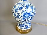 a blue and white vase with a gold base on a table