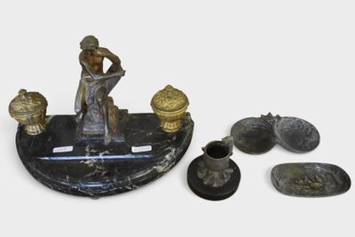 une statue représentant une femme assise sur une table, à côté d'autres objets