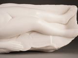 a white sculpture of a woman laying on a pillow