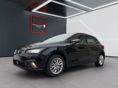 Une voiture noire est garée à l'intérieur d'un immeuble où une pancarte est accrochée au mur.