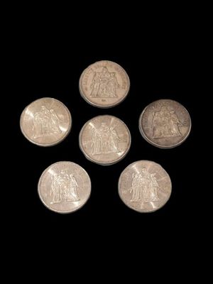 six pièces d'argent sont disposées en cercle sur un fond noir