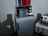un petit réfrigérateur surmonté d'un micro-ondes, à côté d'une petite table
