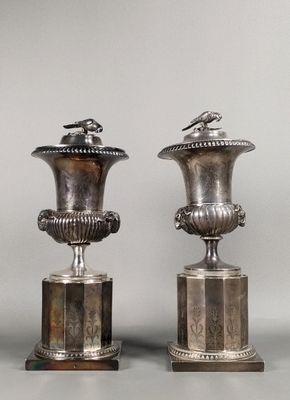 two silver vases sitting on top of a table next to each other