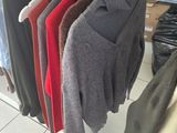 many sweaters hanging on a rack in a clothing store