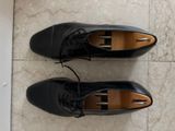 two pairs of black shoes are sitting on a tile floor