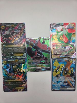 Des cartes du jeu de cartes Pokémon sont alignées sur une surface blanche