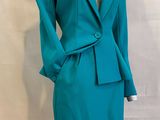 Le mannequin porte un tailleur-jupe de couleur bleu sarcelle.