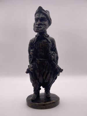 statue noire représentant un homme coiffé d'un chapeau, sur fond blanc
