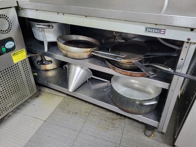des casseroles et des poêles sont posées sur une étagère en métal dans une cuisine