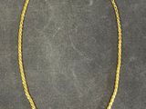 a gold necklace with a chain on a black surface