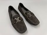 a pair of gray sued shoes with a metal buckle