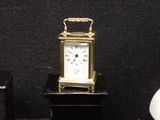 a small clock sitting on top of a table next to a vase