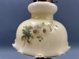 un vase blanc orné de fleurs peintes, posé sur une table