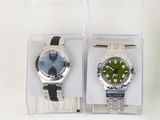 two watches in a clear box on a white surface