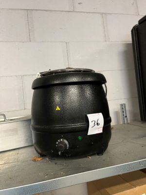 une casserole noire posée sur une étagère, à côté d'un micro-ondes