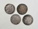 quatre pièces d'argent de tailles et de formes différentes sur une surface blanche