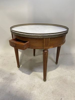 une table ronde avec un plateau en marbre et des pieds en bois