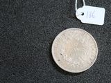 une pièce d'argent posée sur une surface noire, avec une étiquette de prix
