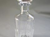 a clear glass bottle with a silver top on a white surface
