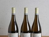 trois bouteilles de vin sont alignées sur une table en bois