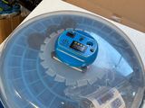 a plastic container with a blue lid sitting on top of a cardboard box