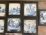 six framed blue and white tile pictures on a brick wall