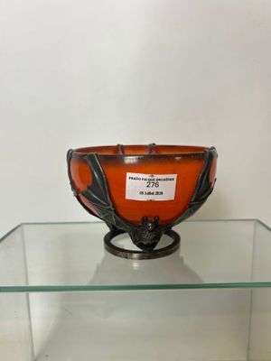 un saladier en verre orange posé sur une table en verre