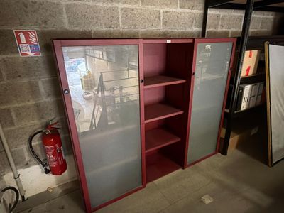 une armoire rouge avec des portes vitrées et un extincteur à l'arrière-plan