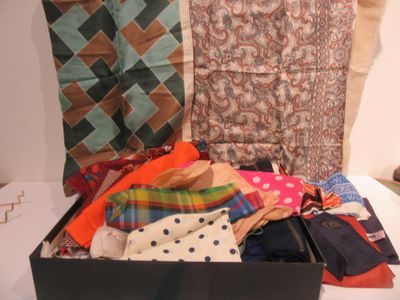 une valise noire remplie de vêtements et de cravates posée sur un lit