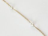 un bracelet en chaîne d'or orné de perles sur fond blanc