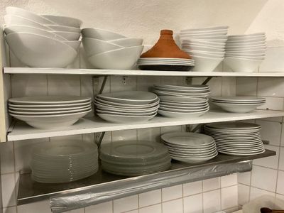 many plates and bowls stacked on the shelves in the kitchen