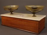 pair of brass bowls on a marble base on a wooden box