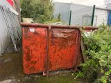 a rusted red dumpster sitting in the middle of a yard