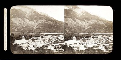 une photo en noir et blanc d'une ville avec des montagnes en arrière-plan