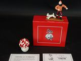 une petite figurine posée sur une boîte rouge