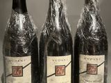 three bottles of wine wrapped in plastic sitting on a counter