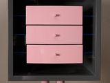 pink and black chest of drawers on a stand against a beige wall