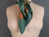 green silk scarf with orange and white stripes on a mannequin torso