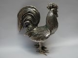 un coq argenté posé sur une surface blanche