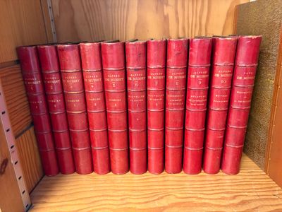 Plusieurs livres rouges sont empilés sur une étagère dans une bibliothèque