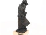statue d'un homme portant un chapeau et une robe, posée sur un socle en bois