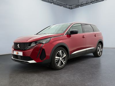 Une voiture rouge est garée dans une grande pièce au sol noir.