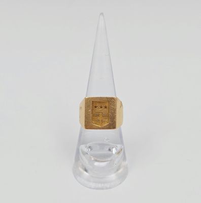 un gros plan d'une bague en or posée sur un socle en verre transparent