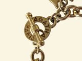 a close up of a gold bracelet with a clock on it